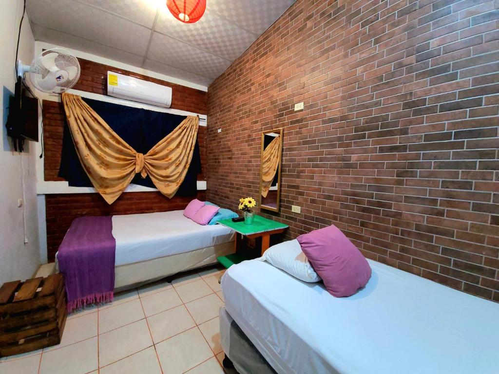 a room with two beds and a brick wall at Hostal Leyendas in León
