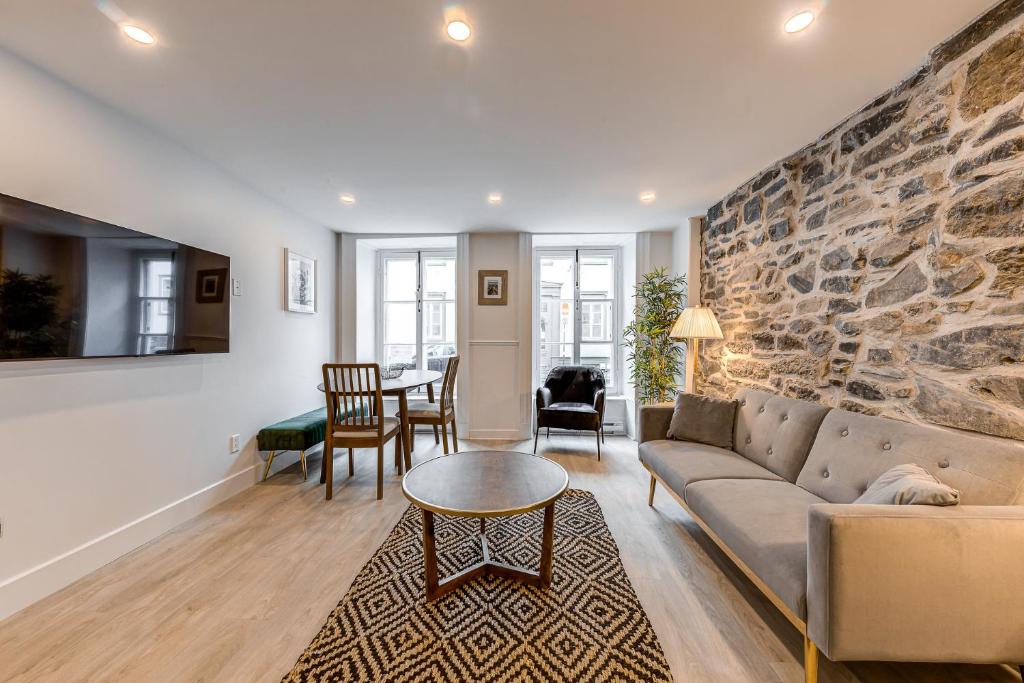 un soggiorno con divano e parete in pietra di Elegant 1 Bedroom Suite a Québec