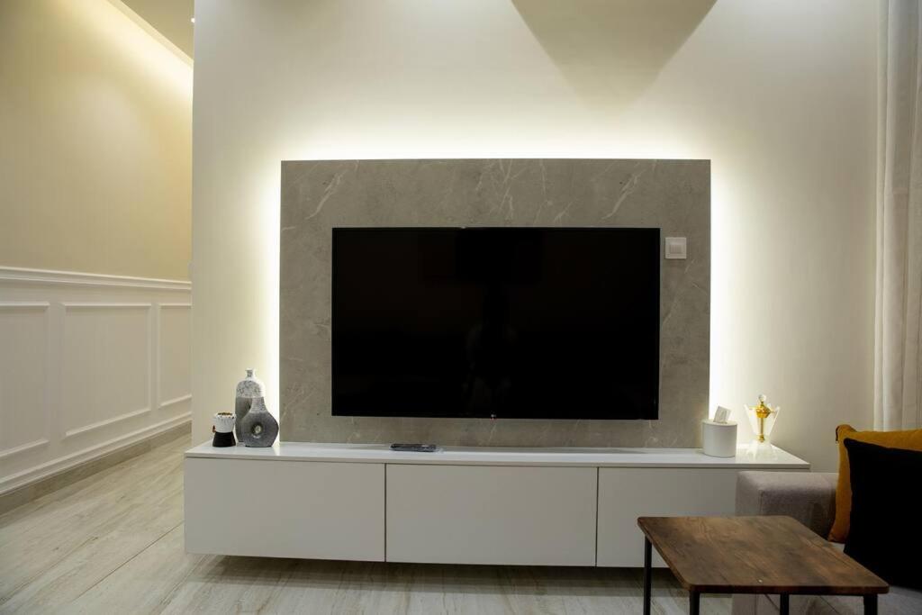 un salon avec une grande télévision sur un mur blanc dans l'établissement شقه فاخره بمدخل خاص وقفل ذكي وثلاث غرف نوم, à Riyad