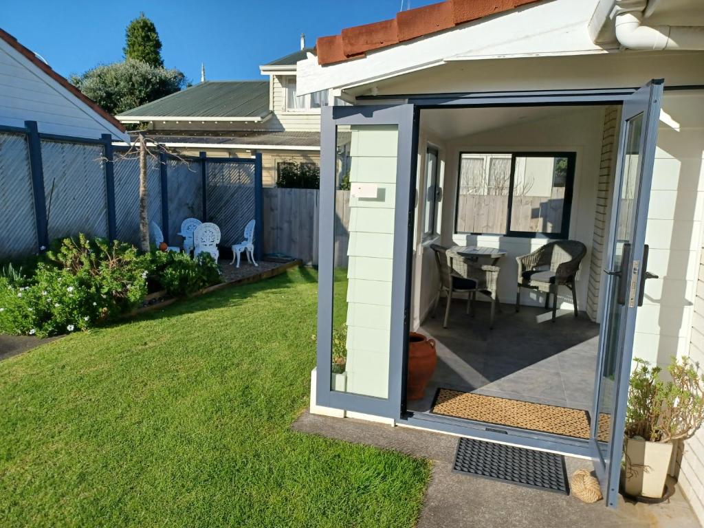a small shed with a table and chairs in a yard at Our Raglan Town House in Raglan