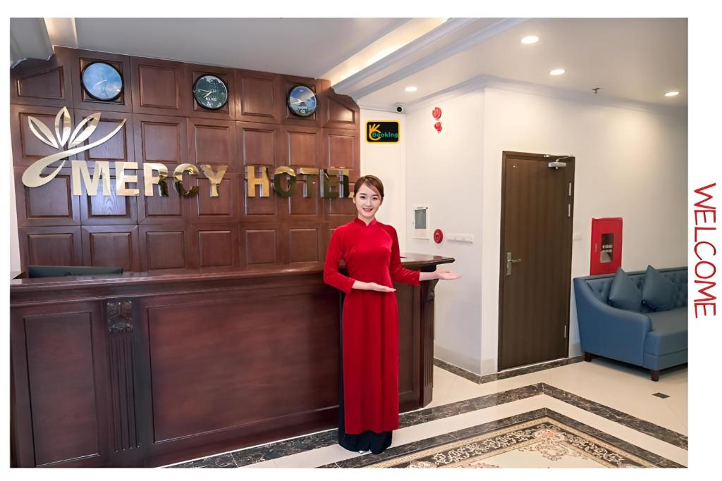 a woman in a red dress standing in a lobby at Mercy Hotel in Hanoi