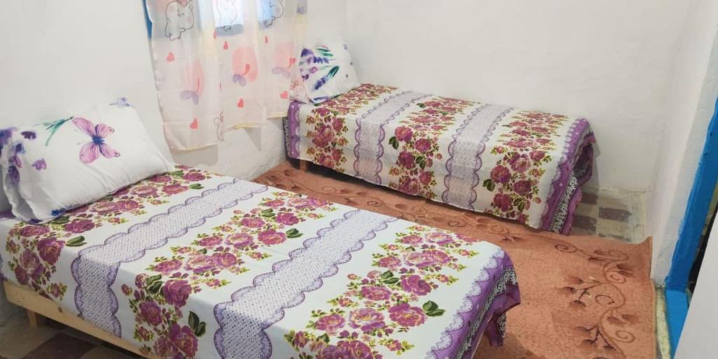 duas camas num quarto com flores em casa de SMR em Chefchaouen
