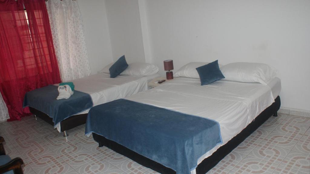 2 Betten in einem Zimmer mit roten Vorhängen in der Unterkunft Guacamayas in Santa Marta