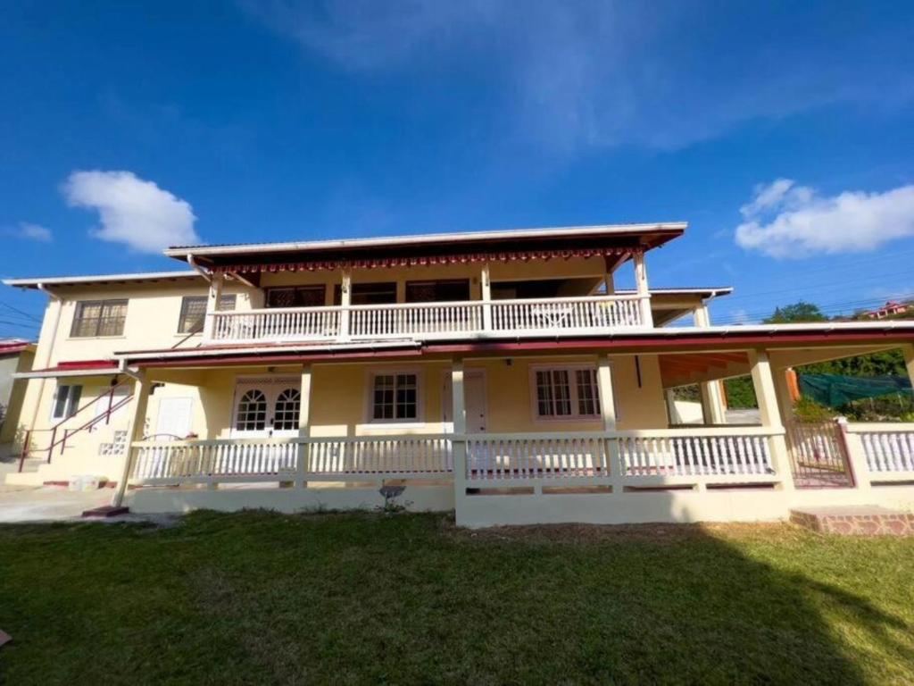 Cette grande maison jaune possède un grand balcon. dans l'établissement Chalet Belizomi Tropical Villa #1, à Gros Islet