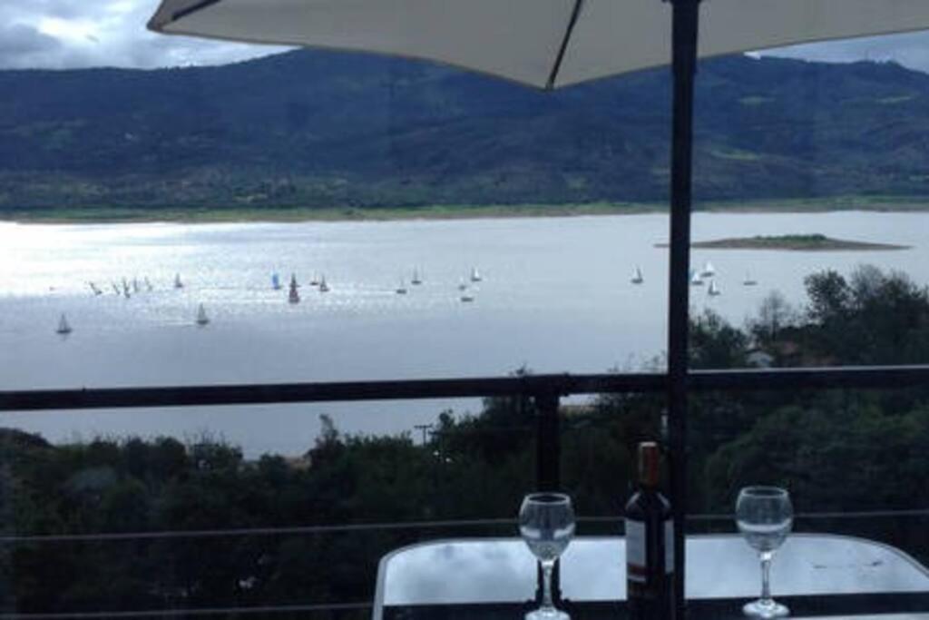 a table with wine glasses and a view of a body of water at Cabaña vista al lago Tominė y Naturaleza Guatavita in Guatavita