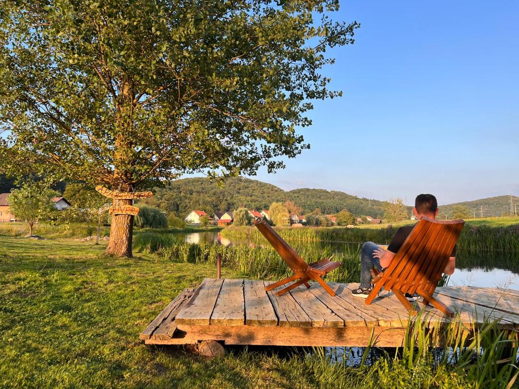 un homme assis sur une chaise sur une table à côté d'un lac dans l'établissement Apartments River, à Otočac