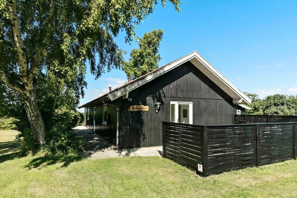 a black barn with a fence in front of it at Solsorten in Hasle