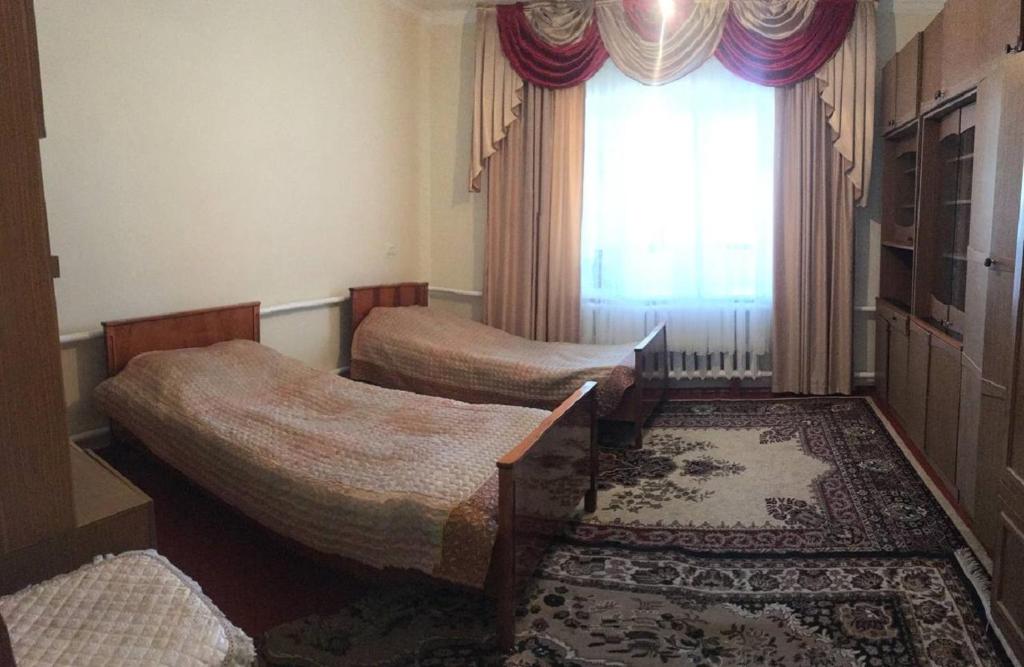 een kamer met 2 bedden, een raam en een tapijt bij Welcome Guest House in Tokmok