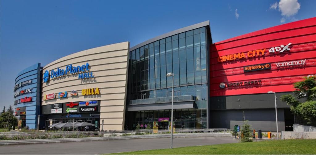 a large shopping center with a red and white building at ВАРНА СИТИ ПАРК С ПАРКОМЯСТО in Varna City