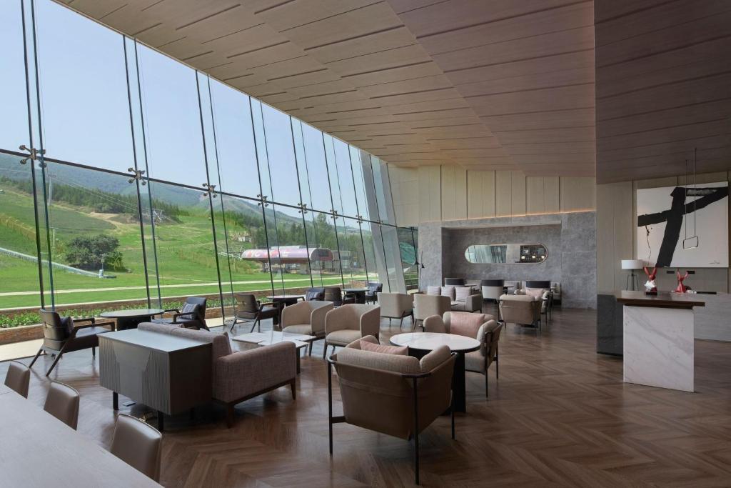 vestíbulo del hotel con sillas, mesas y ventanas en Courtyard by Marriott Chongli, en Zhangjiakou