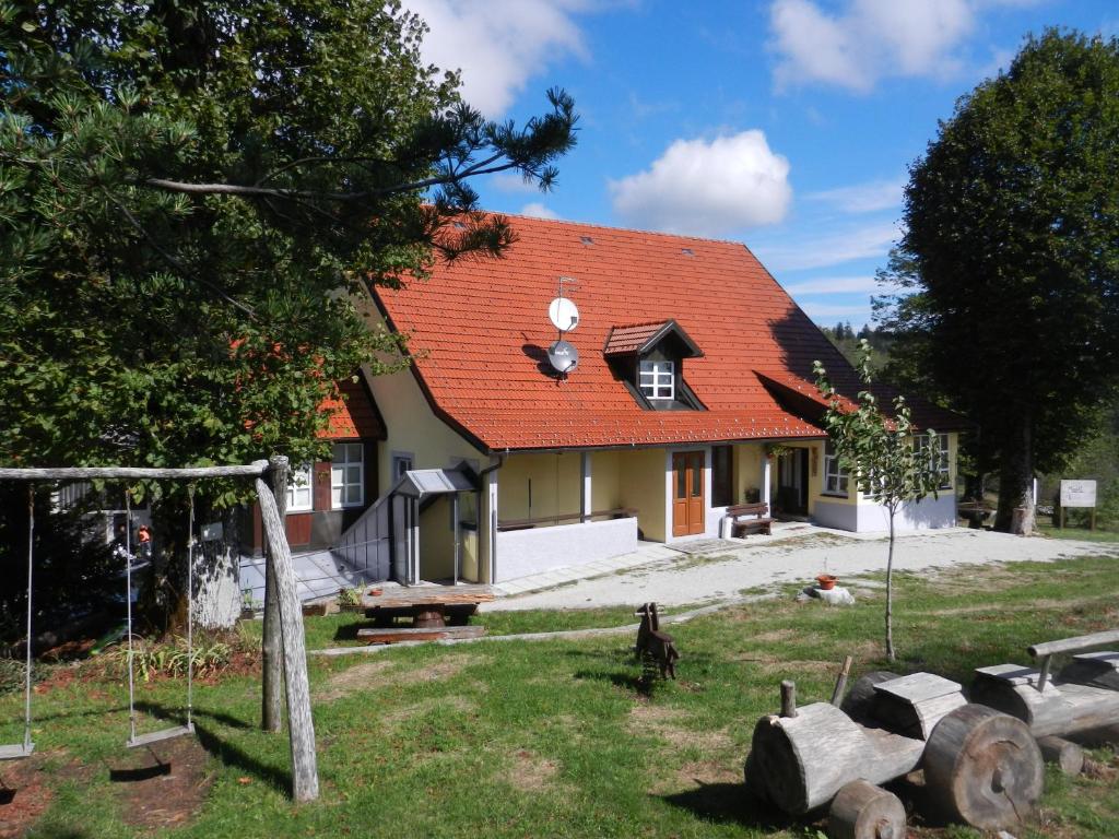 a house with a red roof and a swing at Gostilna Stara Pošta in Podkraj