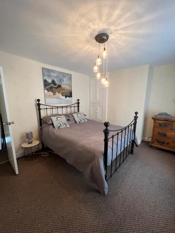 a bedroom with a bed and a chandelier at Park cottage High Crompton in Shaw