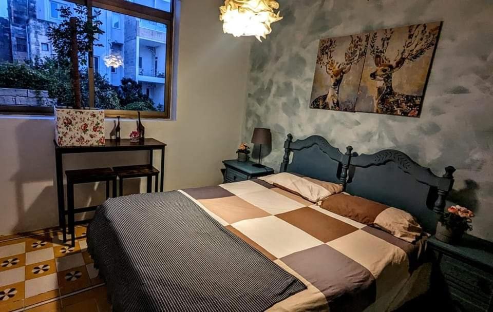 a bedroom with a bed and a desk and a window at Townhouse 88 cloudy room in Sliema