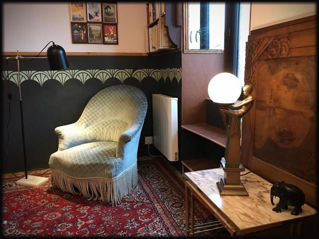 un salon avec une chaise et une lampe dans l'établissement Maisonnette art déco, à Choriol