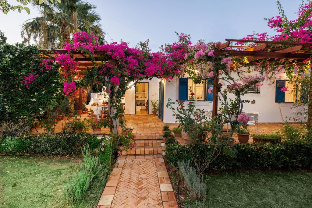 un jardín con una pérgola llena de flores rosas en Villa in the Garden, en Kokkíni Khánion