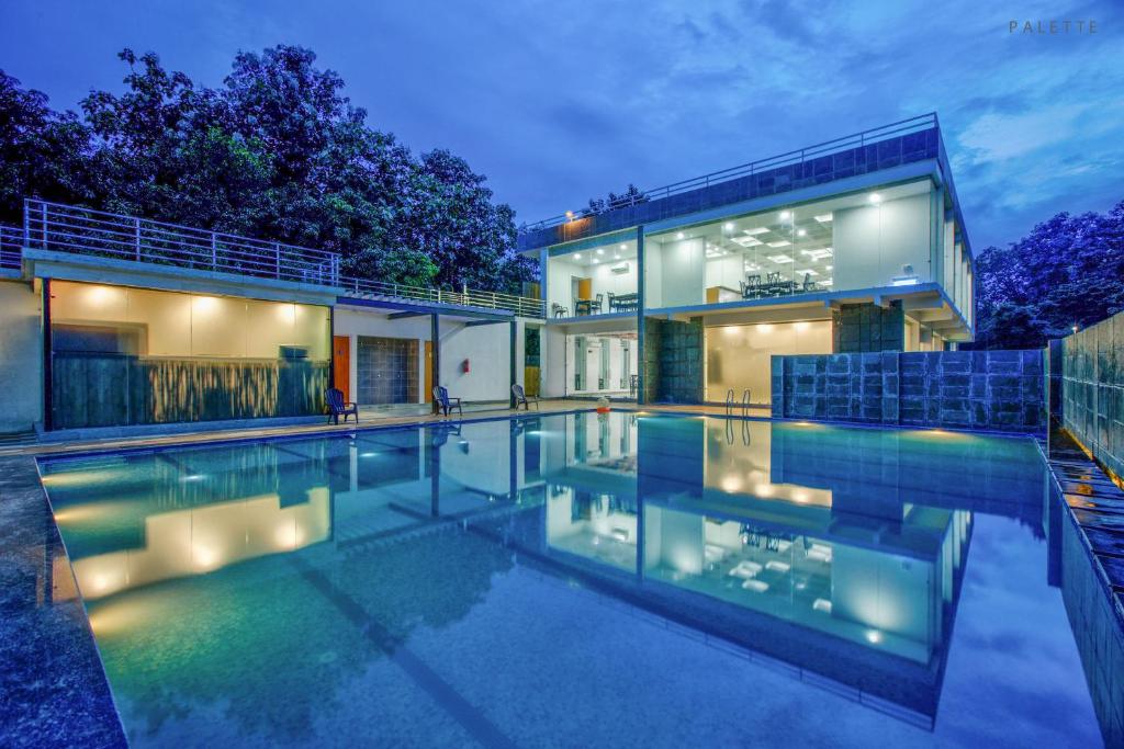 a house with a swimming pool in front of a house at The Cloyster Resort and Spa in Rāmnagar