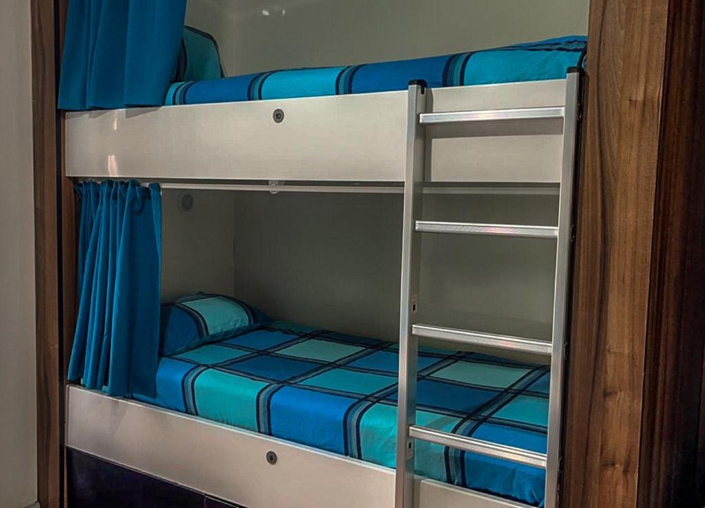 two bunk beds with blue sheets and a ladder at The Liverpool Pod Travel Hostel in Liverpool