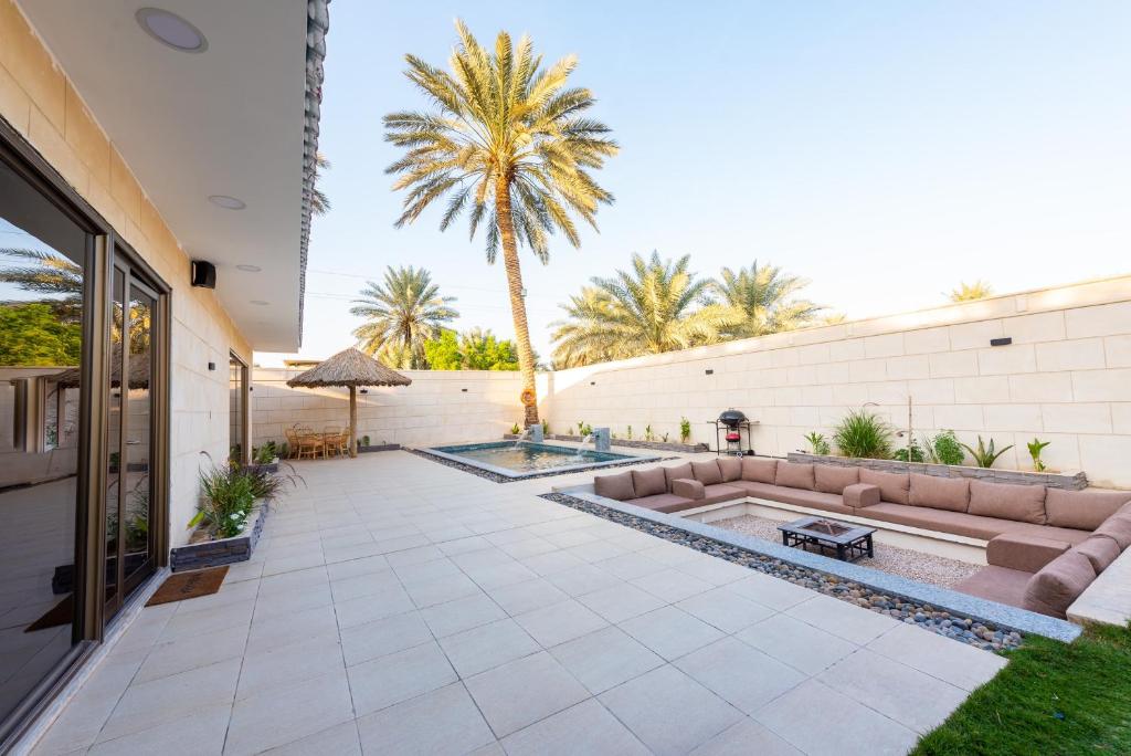 un patio al aire libre con piscina y palmeras en منتجع كالوتارا, en Banī Ma‘n