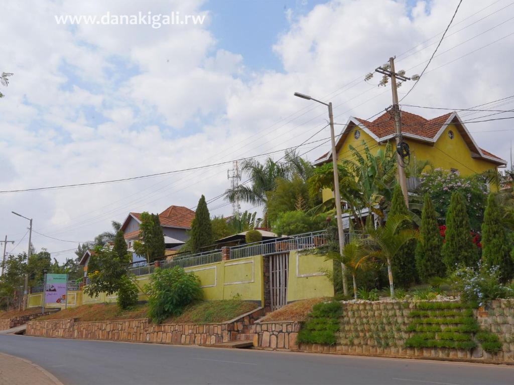 una casa amarilla al lado de una calle en DANA KIGALI HOTEL en Kigali