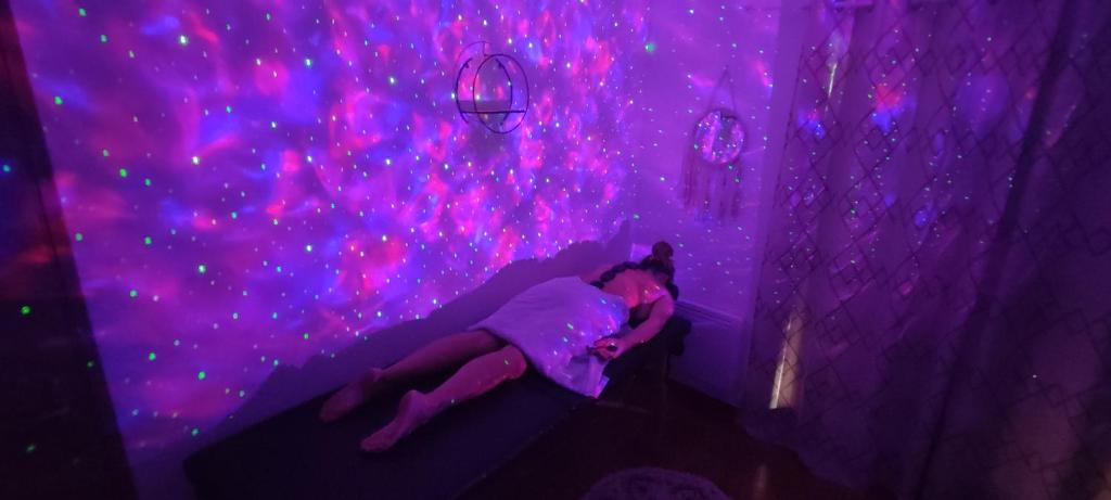 a woman laying on a bed in a purple room at Chambre d&#39;hôte Amouratcha in Fabrègues