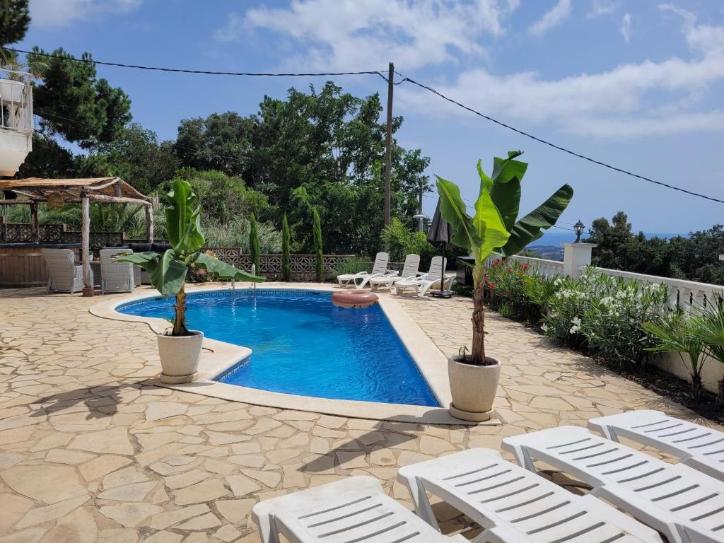 uma piscina com cadeiras brancas e uma piscina em Casa Feliç (10-12 personen) em Lloret de Mar