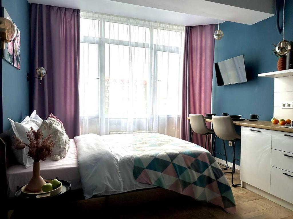 a bedroom with a bed and a desk and a window at BAYHOUSE - Уютные апартаменты в микрорайоне Жетысу 4 in Imeni Stalina