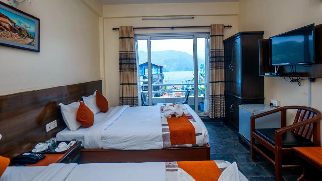 a hotel room with two beds and a balcony at Hotel Kunja in Pokhara