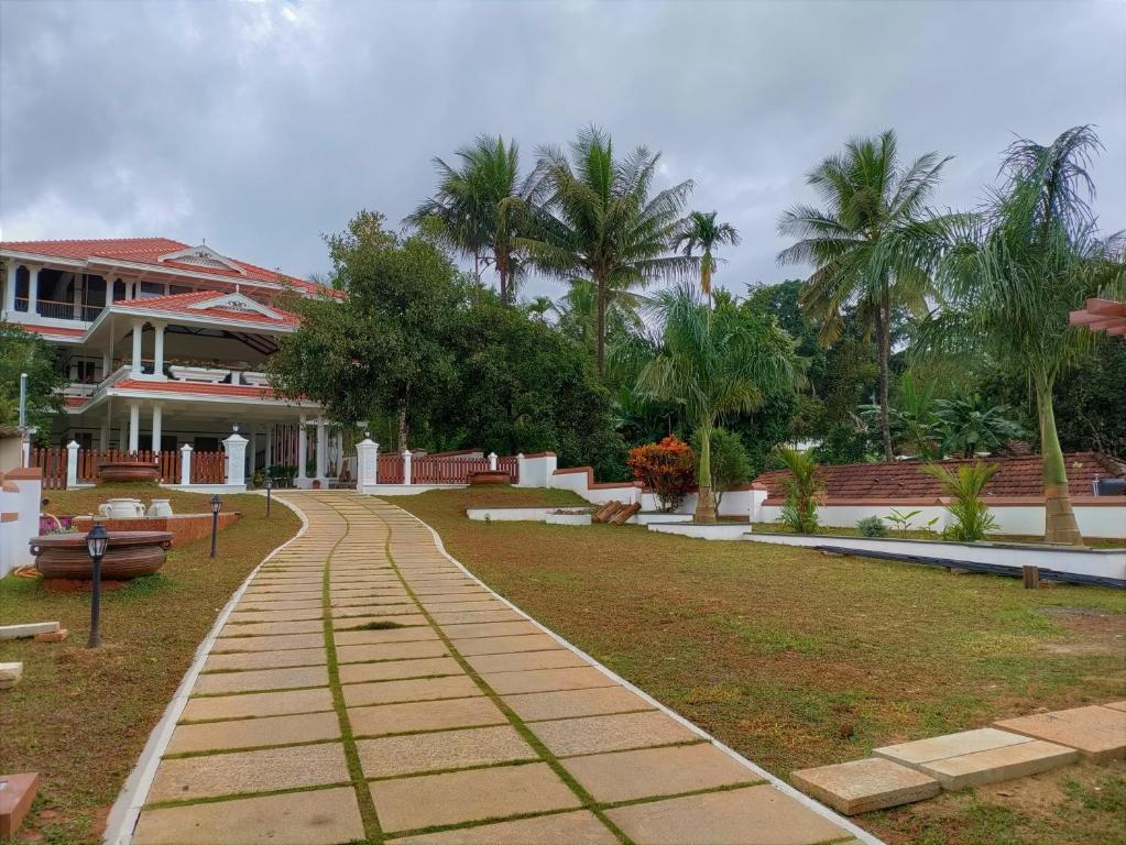 a walkway in front of a house with palm trees at The Cana's Coorg in Ammatti
