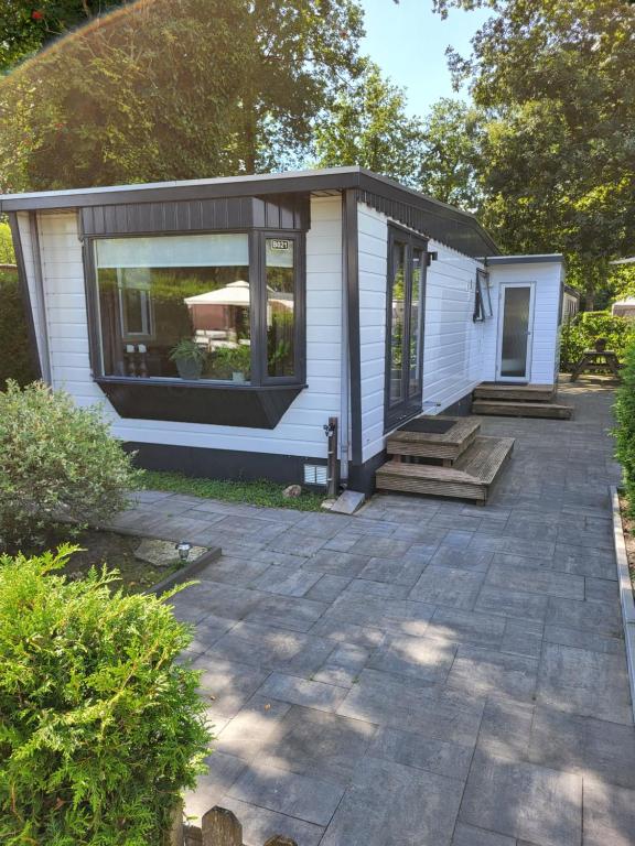 ein kleines weißes Haus mit einer Veranda und einer Terrasse in der Unterkunft Chalet Renswouw in Renswoude