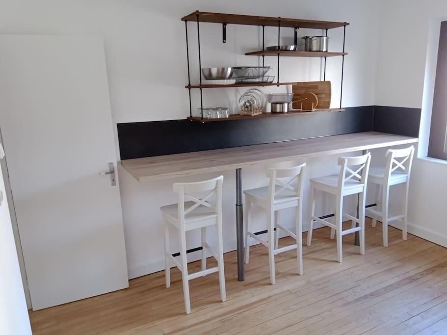 een keuken met een bar met witte krukken bij La petite suisse 2 in Jezainville