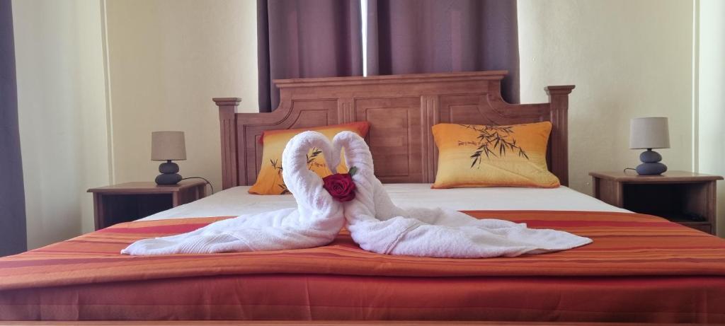 Dois cisnes vestidos de branco estão sentados numa cama em Chez Syl 