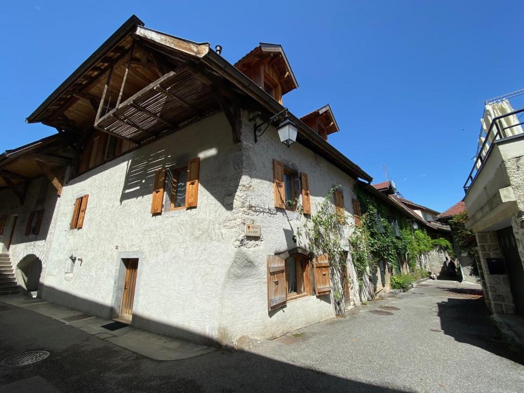 a white building with wooden windows on a street at Duplex à 120 m du lac d'Annecy in Duingt