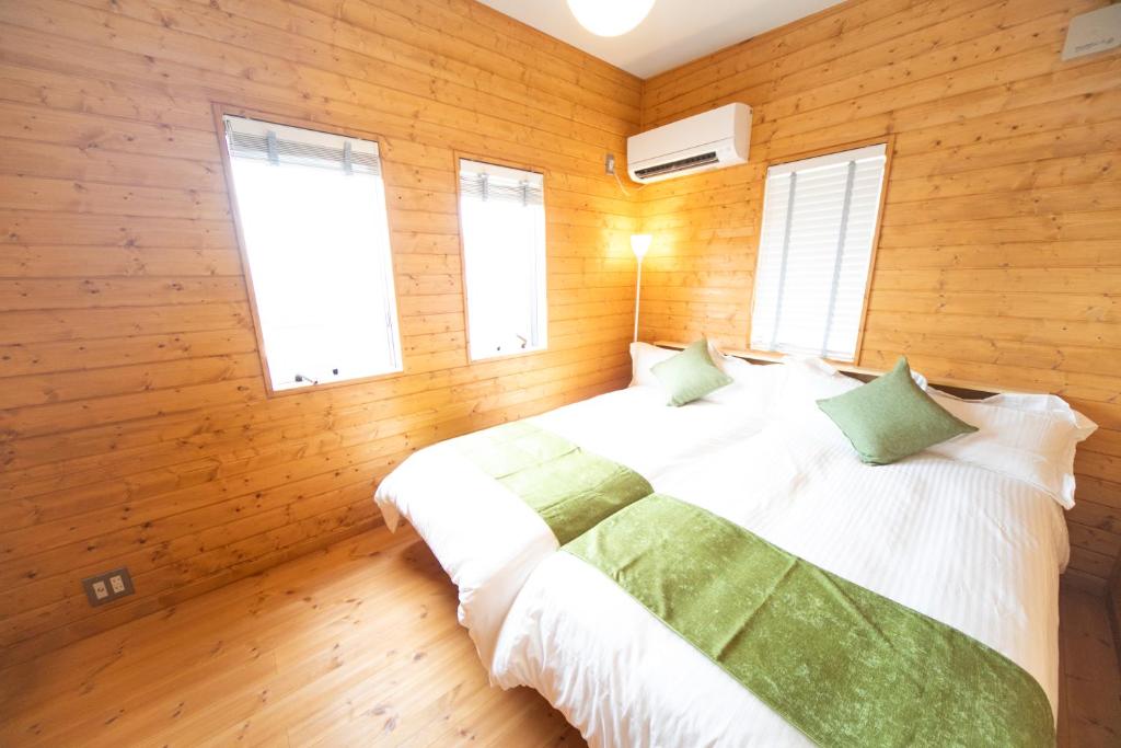 a bedroom with a bed with wooden walls and windows at Awaji Seaview Resort in Nojima in Kusumoto