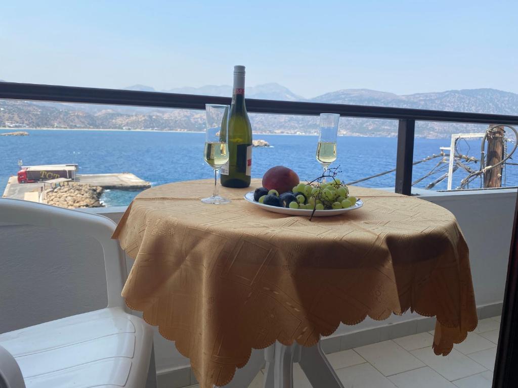 a table with a plate of fruit and wine glasses at Dolphin Hotel Apartments in Karpathos