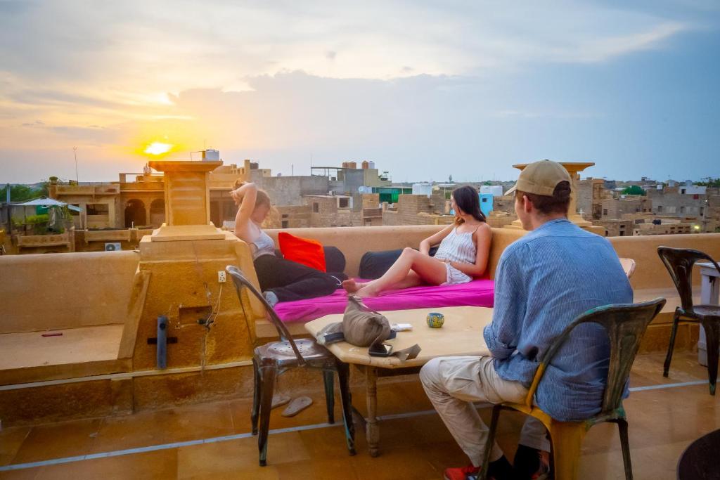 a group of people sitting on a roof watching the sunset at Open Road Hostel and Cafe in Jaisalmer