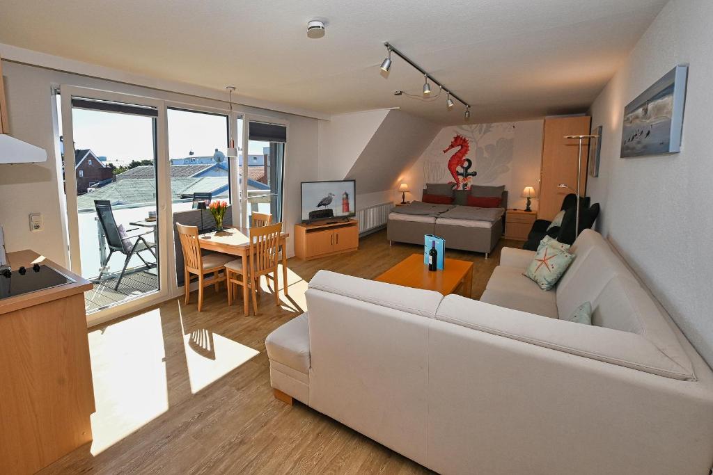 a living room with a white couch and a table at Ferienwohnung NORDIA Allee und See in Büsum