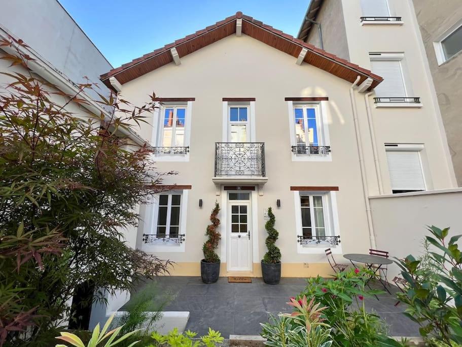 une maison blanche avec deux plantes en pot devant elle dans l'établissement Villa La Roseraie, à Vichy