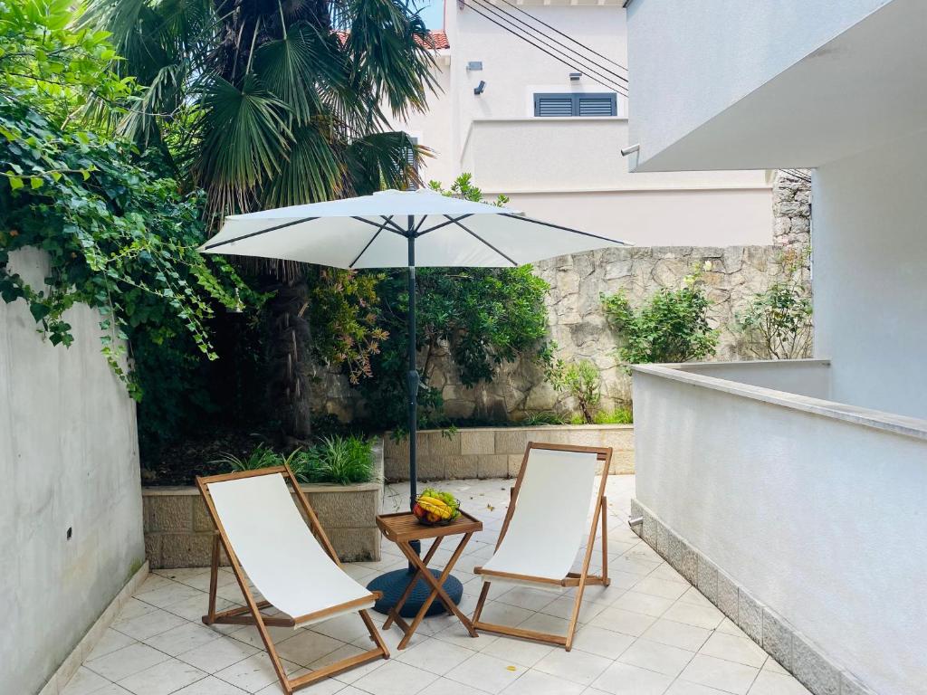 Duas cadeiras e uma mesa com um guarda-sol num pátio em PaFi Apartment em Dubrovnik