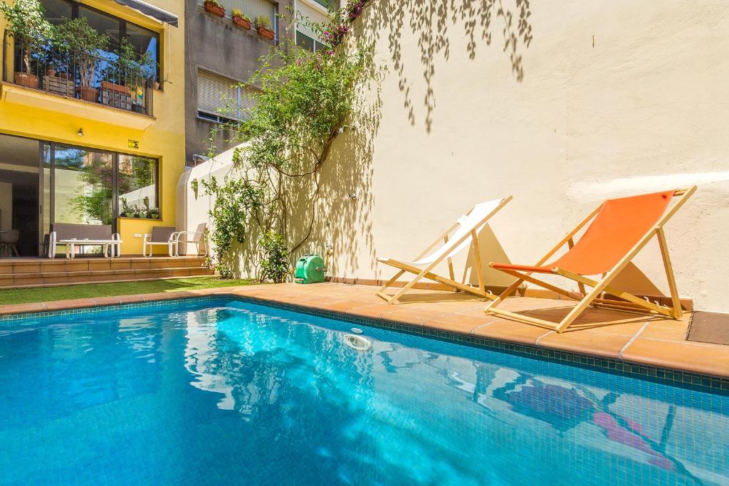 2 sillas sentadas junto a una piscina en L'alzina Apartment, en Barcelona