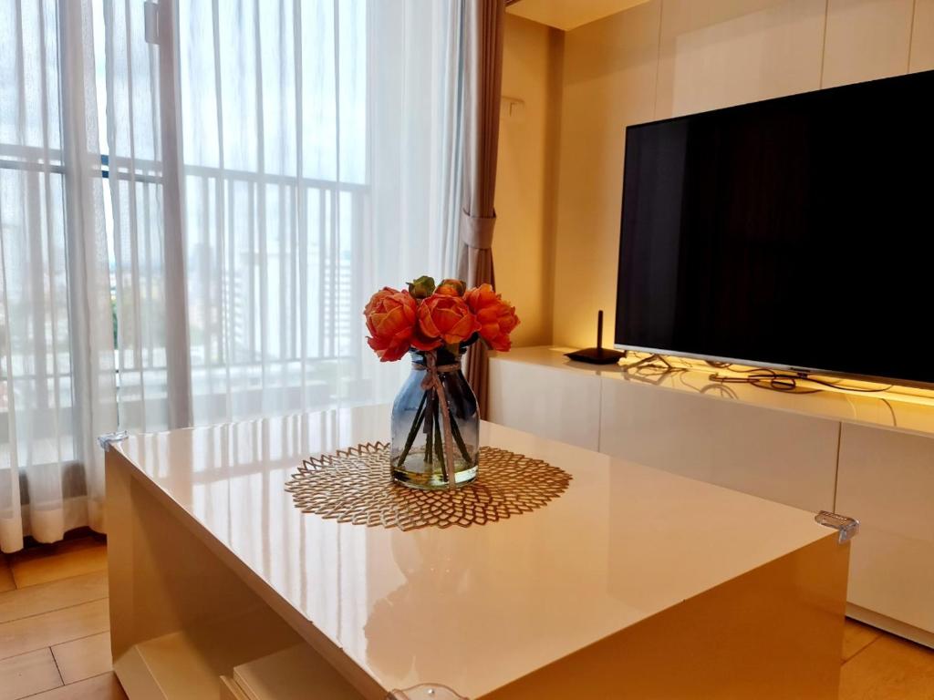 a vase of flowers sitting on a table next to a tv at 2 Bedroom apartment near Chiang mai Night Bazzar in Chiang Mai
