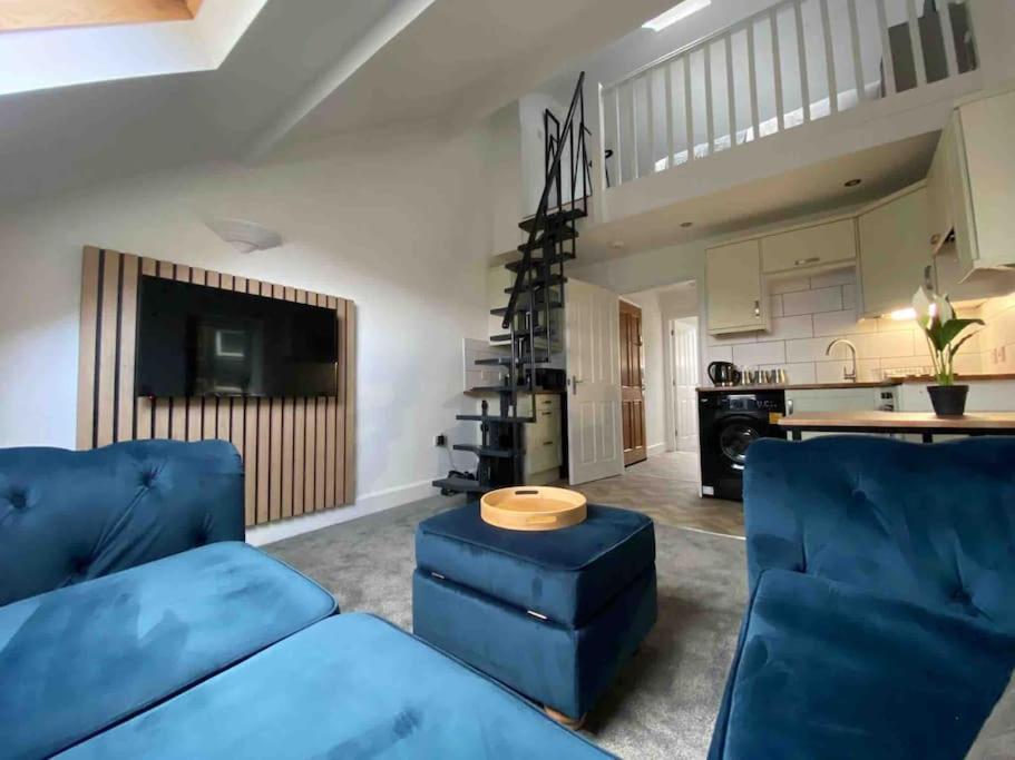 a living room with a blue couch and a kitchen at Wards House Loft Apartment, Matlock in Matlock