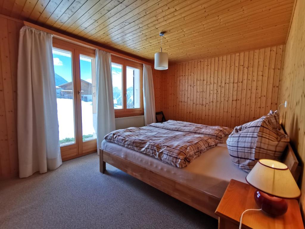1 dormitorio con cama y ventana grande en CHALET HÜTTLE - authentisch, ruhig, mitten im grün, en Grächen