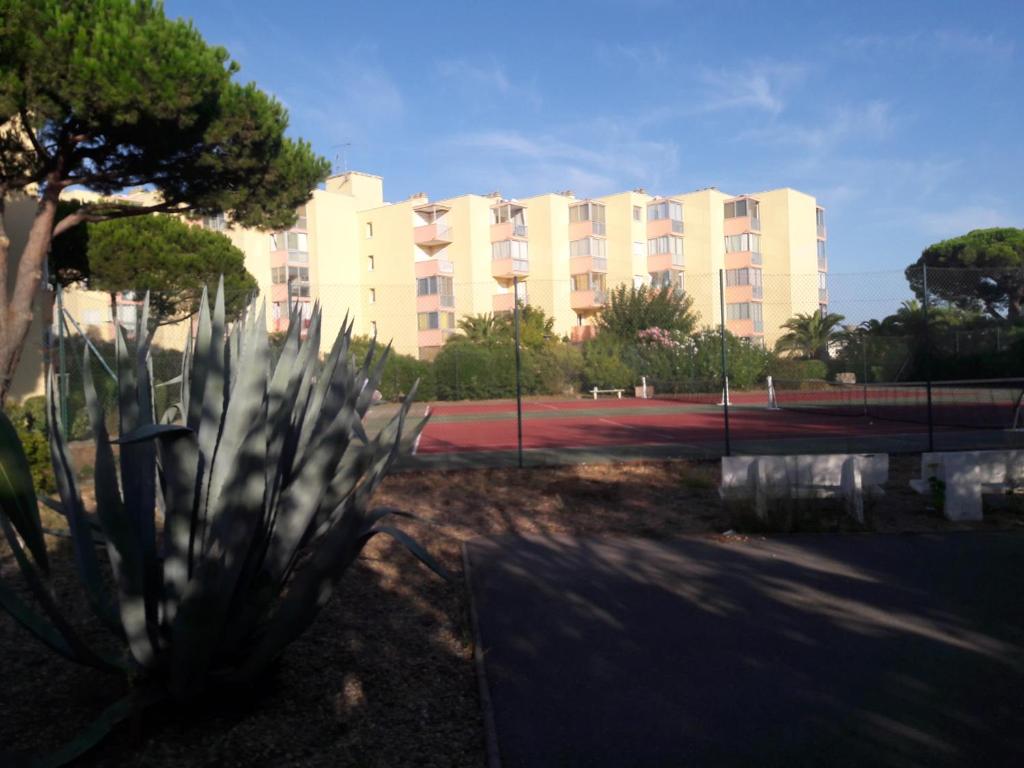- une vue sur un bâtiment et un court de tennis dans l'établissement Joli appt 2 chambres et studio avec parking dans résidence ombragée et calme 5mns plage et commerces, au Grau-du-Roi
