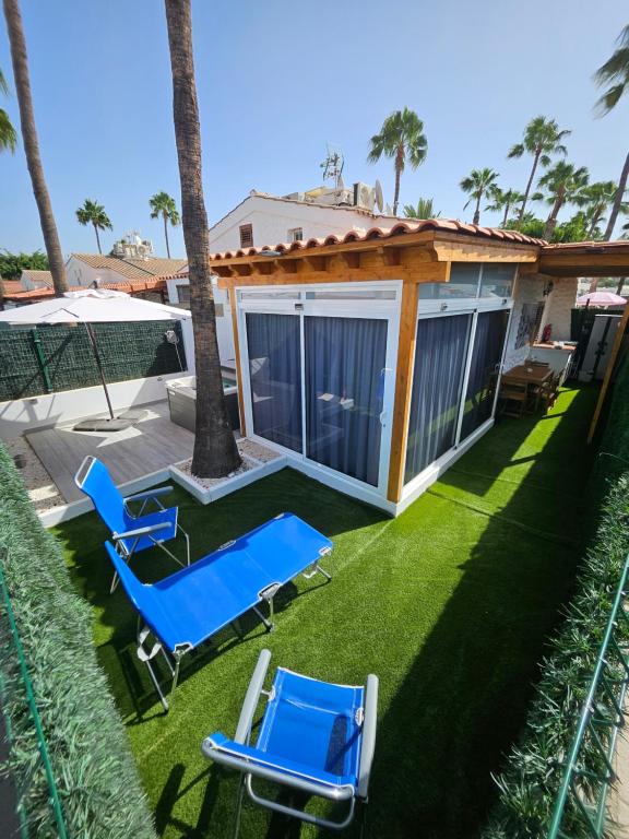マスパロマスにあるChalet Luxury with privacy and Jacuzziの青い椅子2脚付きの庭と家