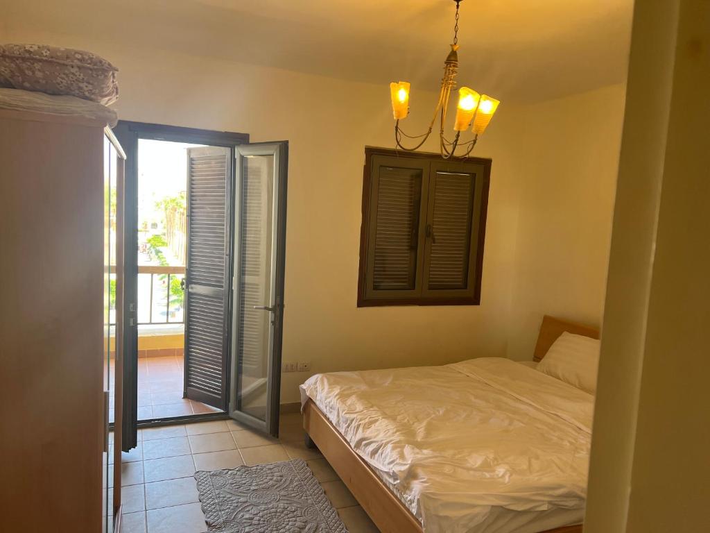 een slaapkamer met een bed, een raam en een kroonluchter bij Marina apartment 2 in Aqaba