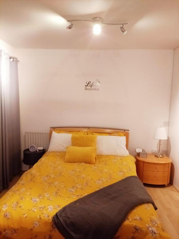 um quarto com uma cama amarela e 2 almofadas amarelas em HomeStay Cosy Studio em Birmingham