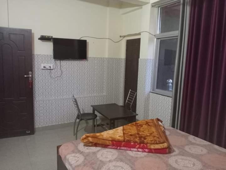um quarto com uma cama, uma mesa e uma televisão em Shivangari Home Stay By WB Homes em Mandāli