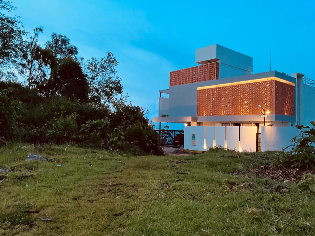 una casa en la cima de una colina con un campo en Golden Creeper, Luxe villa, en Kodaikanal