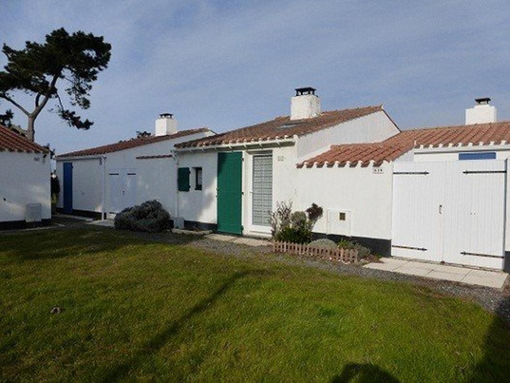 une rangée de maisons blanches avec une cour d'herbe dans l'établissement Charmante maison proche mer avec piscine chauffée, tennis et jardin - Bretignolles-sur-Mer - FR-1-224A-18, à Bretignolles-sur-Mer