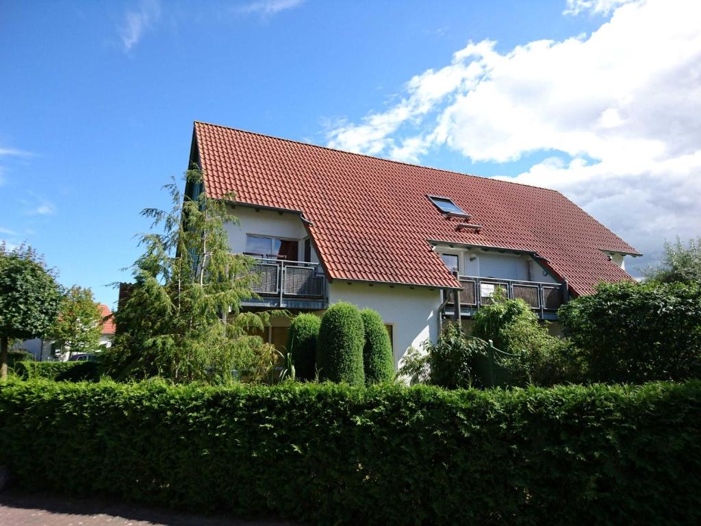 a house with a red roof and some bushes at Weidenweg 4d in Ostseebad Karlshagen